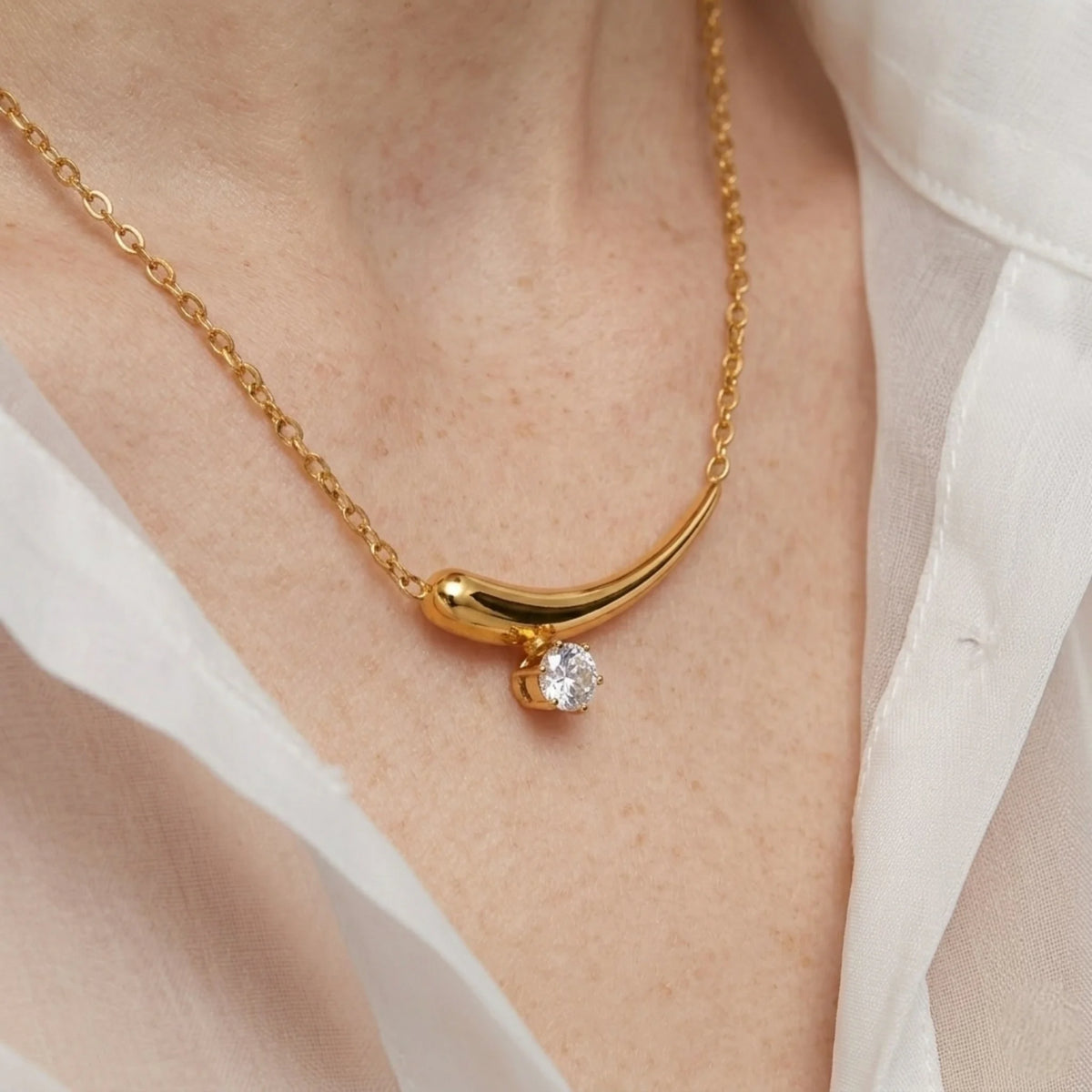 BEHI MILANO Lena Necklace — close-up of model wearing gold zircon crescent horn necklace on neckline