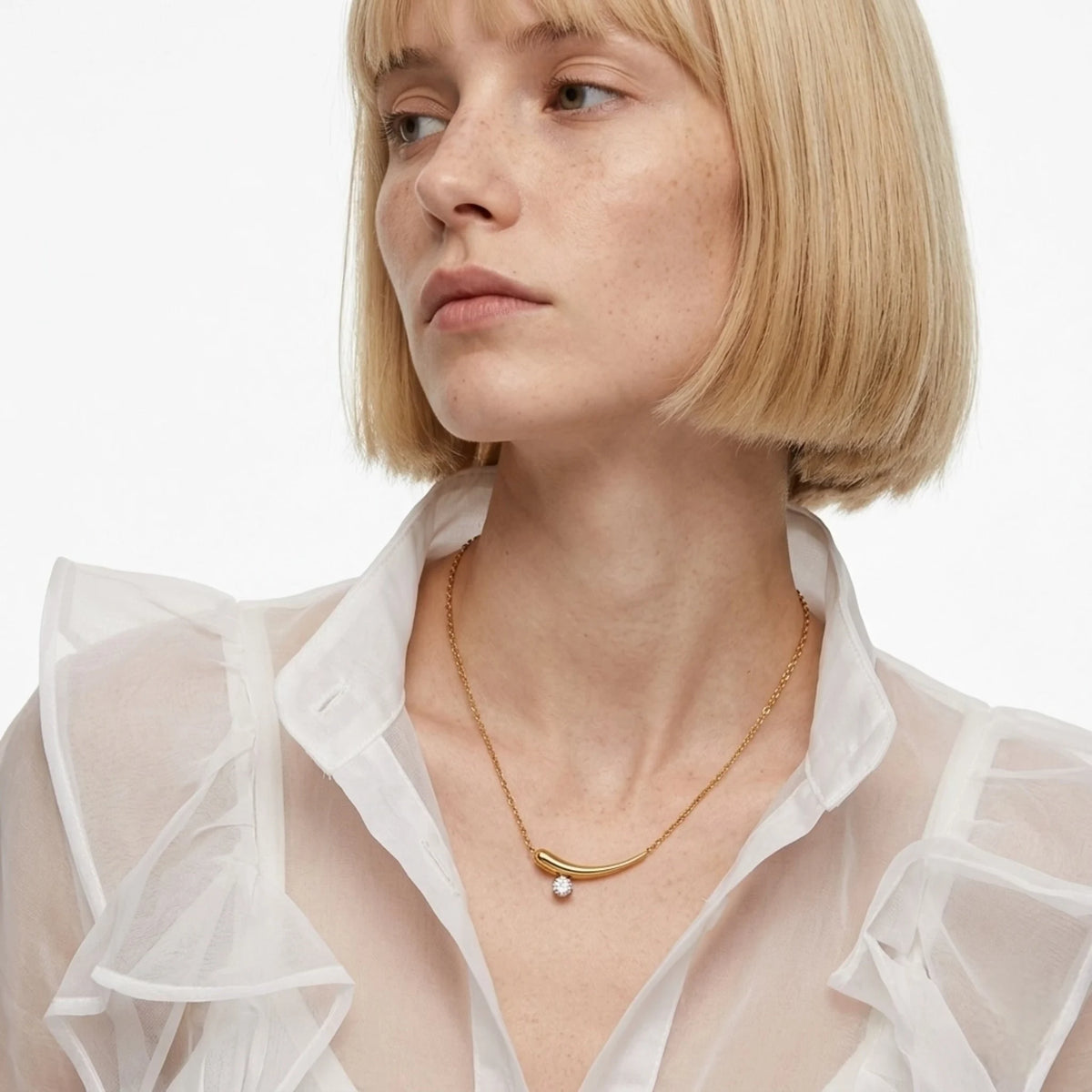 BEHI MILANO Lena Necklace — model wearing gold curved horn zircon pendant with white sheer blouse