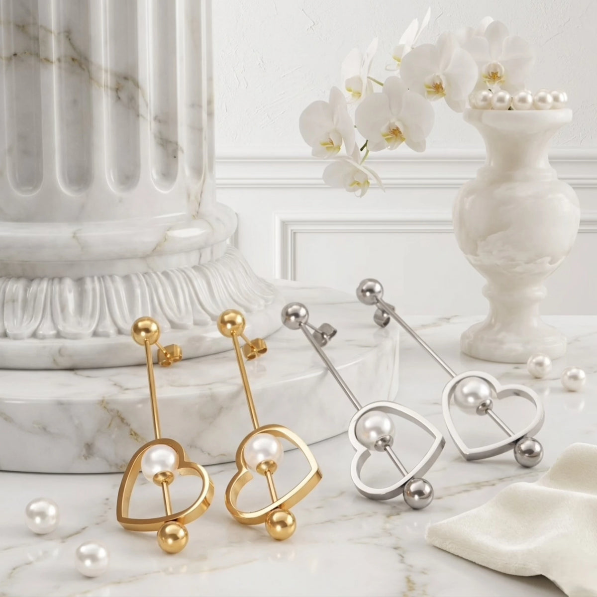 BEHI MILANO Leona Earrings — gold and silver linear heart pearl drop earrings arranged on studio marble