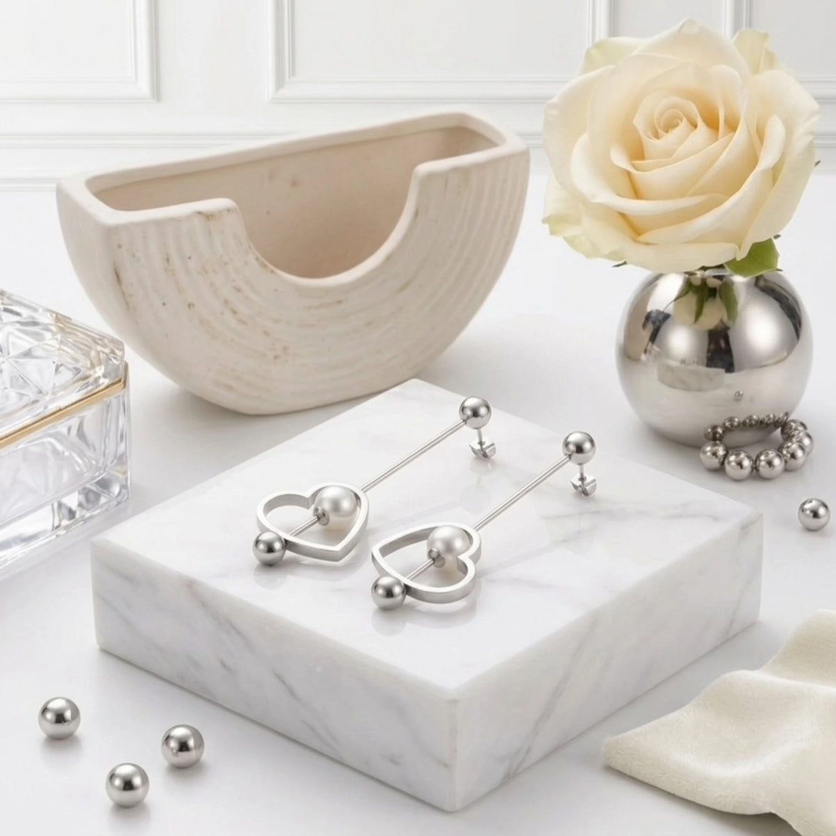 BEHI MILANO Leona Earrings — silver heart pearl drop earrings on white marble tray with roses