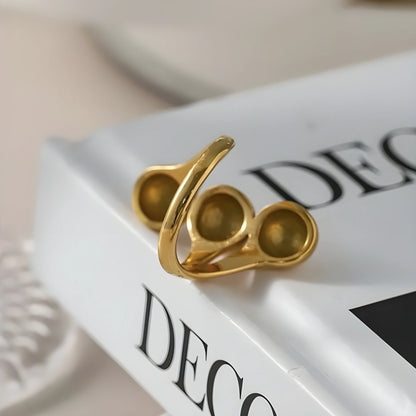 BEHI MILANO Letiz Ring — gold open sculptural ring styled on white coffee table book