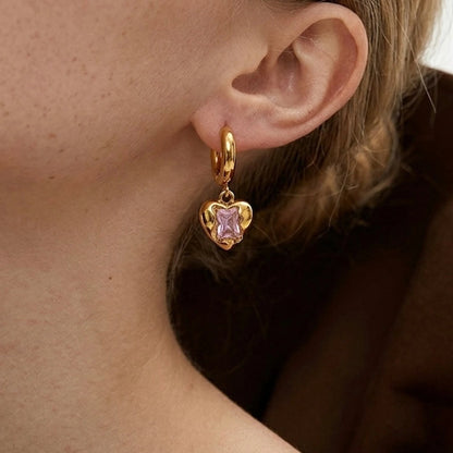 BEHI MILANO Lidia Earrings — close-up of model ear wearing gold huggie hoop with pink heart charm